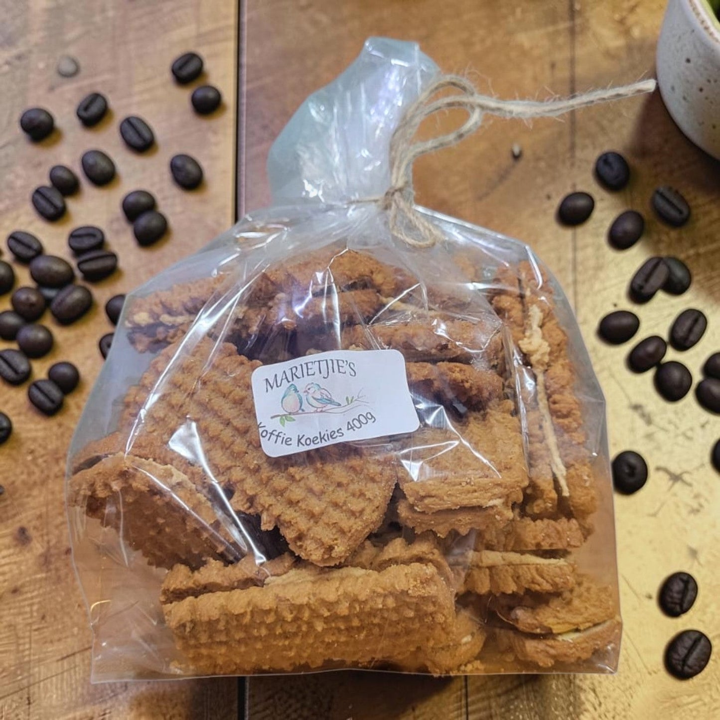 Die Spens Clarens Marietjies Koffie Koekies, crisp coffee-flavoured biscuits in a clear bag tied with twine, 400g.