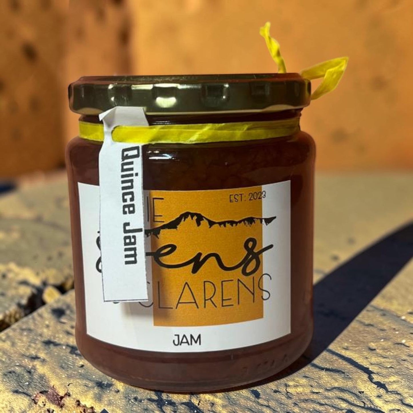 Die Spens Clarens Quince Jam in a glass jar with a yellow ribbon and white label. Artisanal fruit preserve.
