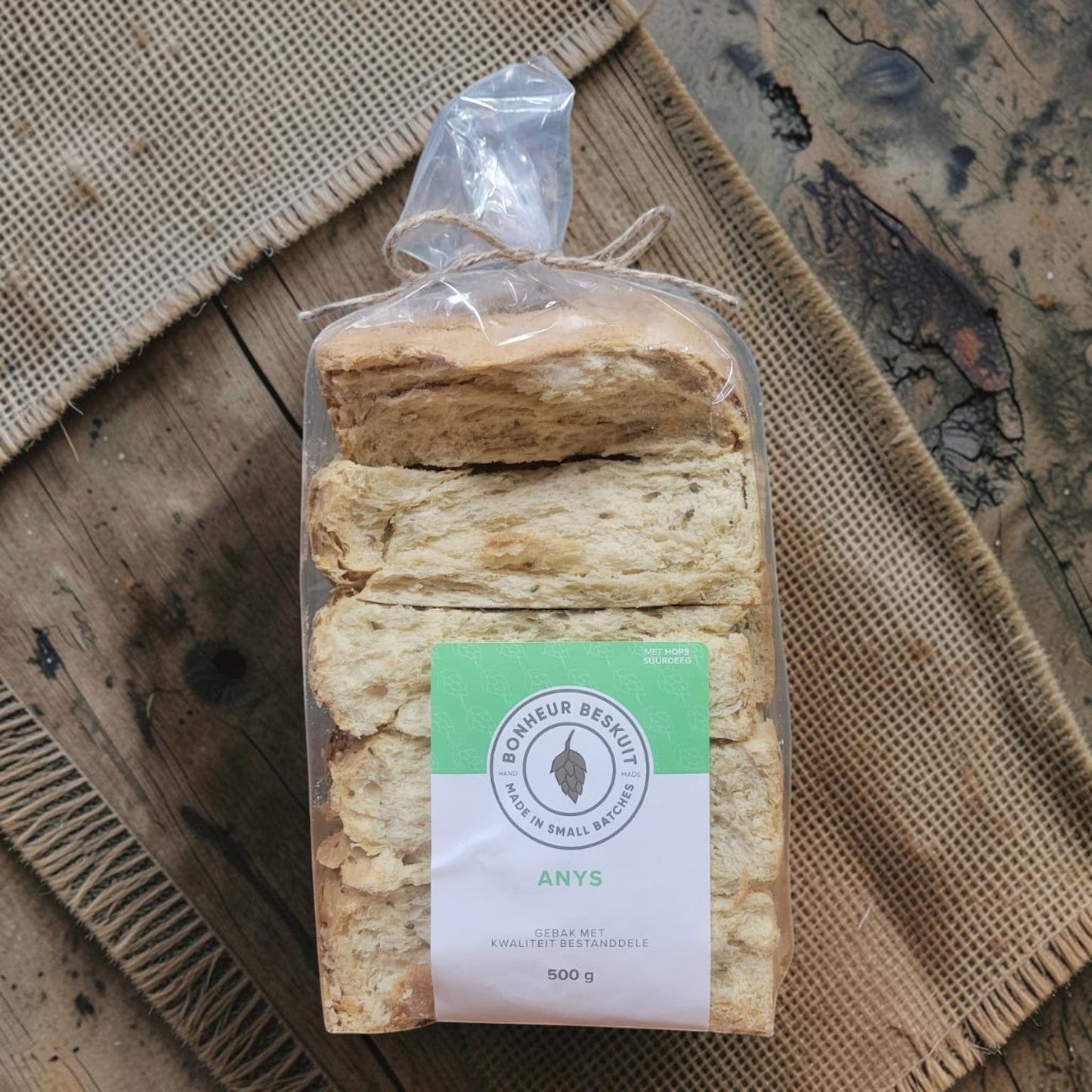Die Spens Clarens Aniseed Hops biscuits in a clear plastic bag, tied with twine, showing their golden-brown color and textured surface.