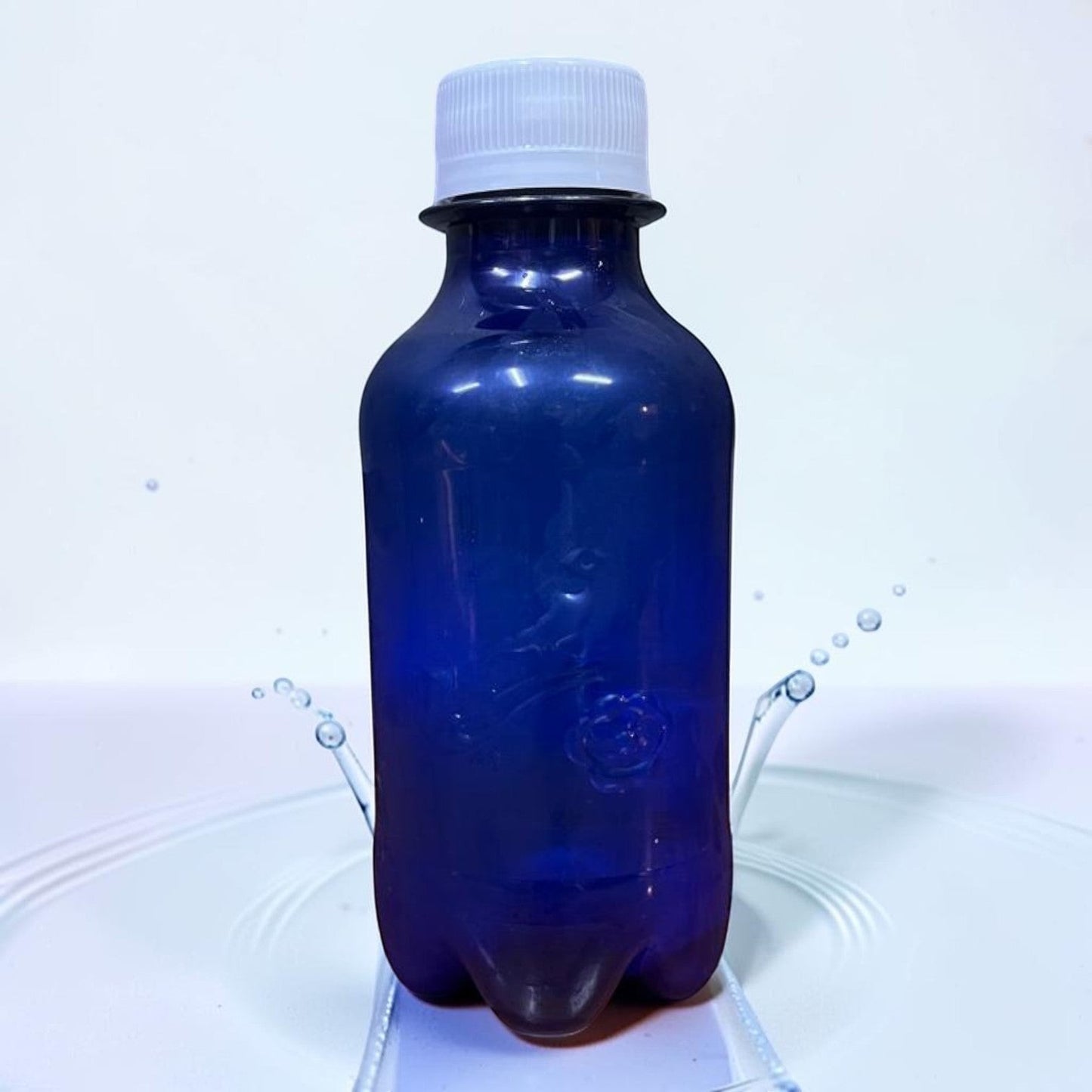 Die Spens Clarens 500ml dark blue plastic bottle of Babylonstoren sparkling water with a white cap, surrounded by water splashes.