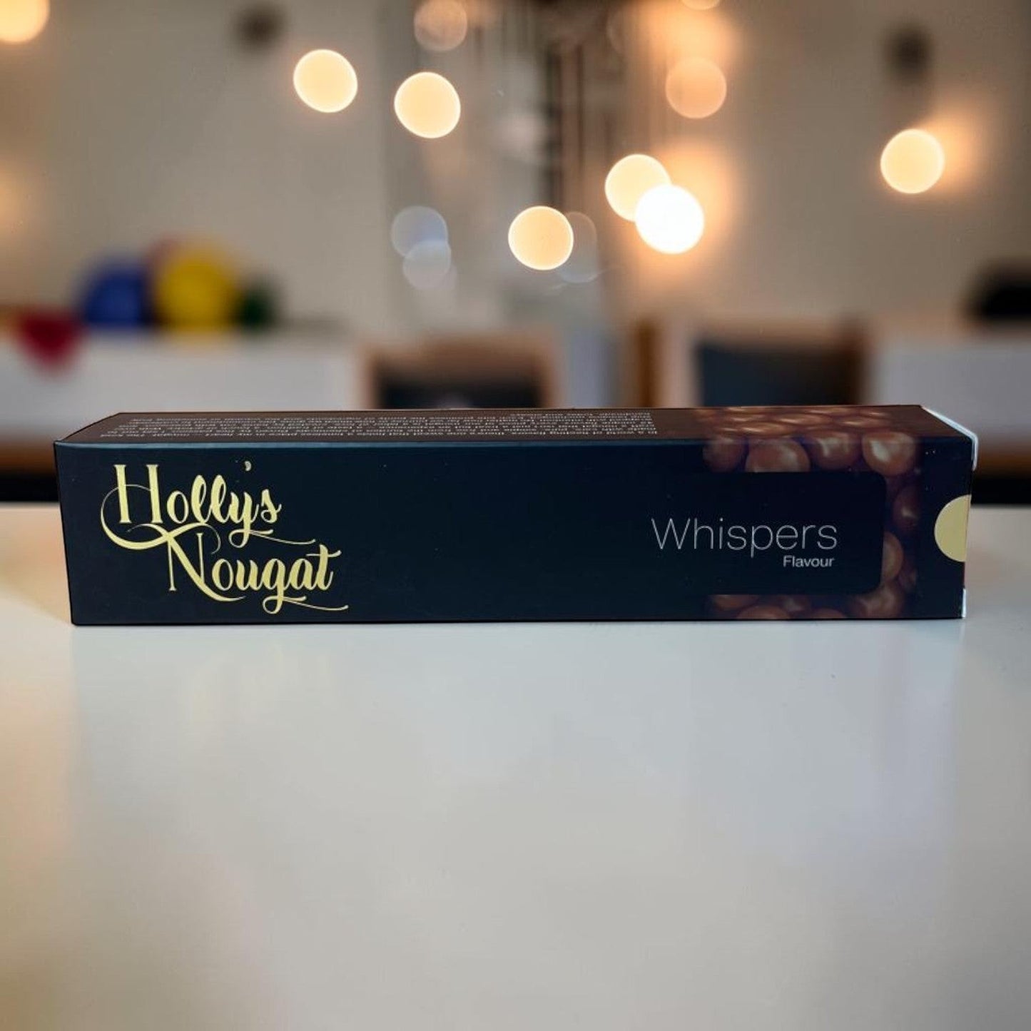 Die Spens Clarens Holly's Nougat Whispers flavour box, featuring golden text on a dark background with an image of nougat pieces.