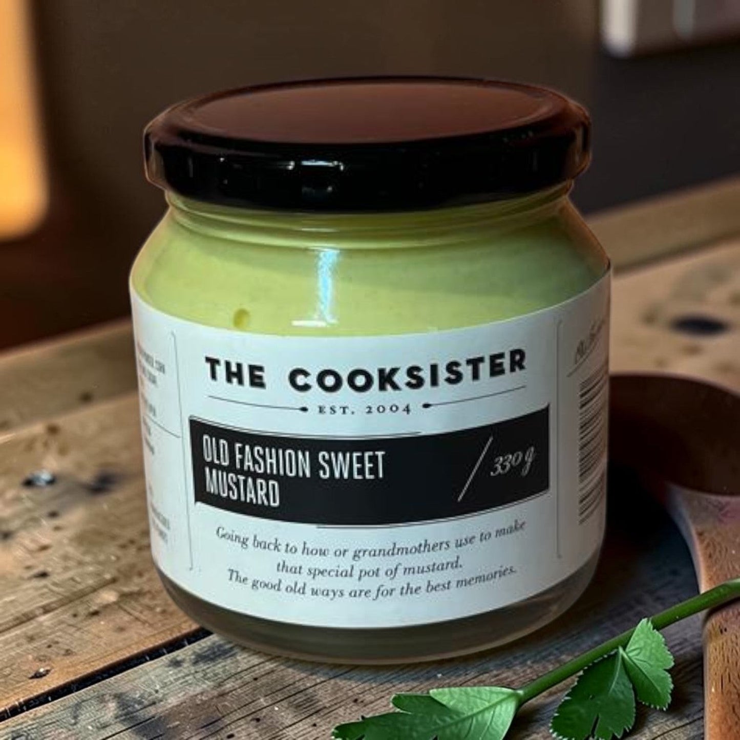 Die Spens Clarens The Cooksister Old Fashion Sweet Mustard in a glass jar with a black lid. Smooth, pale yellow mustard.