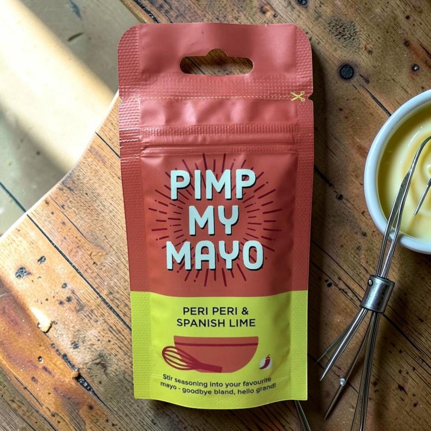 Die Spens Clarens Pimp My Mayo Peri Peri & Spanish Lime seasoning pouch with a whisk and bowl of mayonnaise.