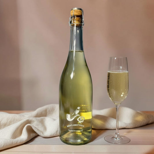 Die Spens Clarens Babylonstoren Vonkel Druiwesap sparkling grape juice in a clear bottle with a cork stopper and a glass of the beverage.