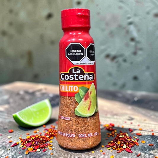 Die Spens Clarens La Costeña Chilito Chilli & Lime Spice blend in a red shaker bottle, with lime wedges and chili flakes.