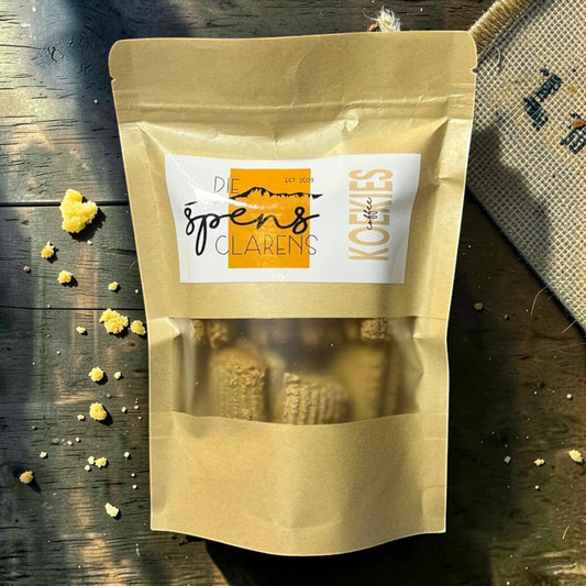 Die Spens Clarens small coffee biscuits in a resealable brown pouch, with crumbs scattered on a wooden surface.
