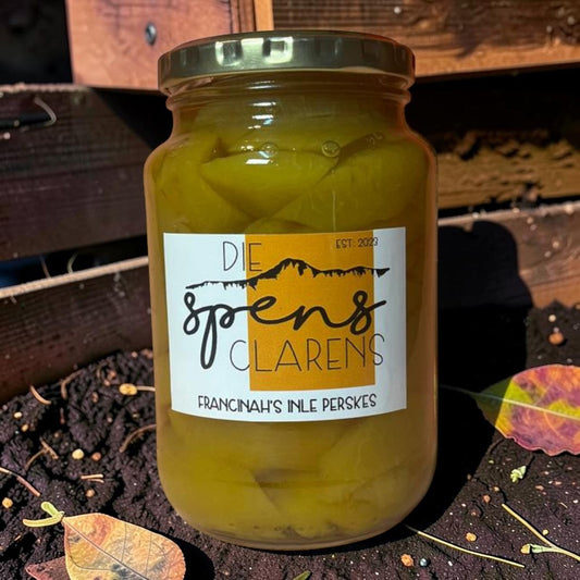 Die Spens Clarens Francinah's Inle Perskes preserved peaches in a glass jar, showcasing homemade goodness and traditional South African flavor.
