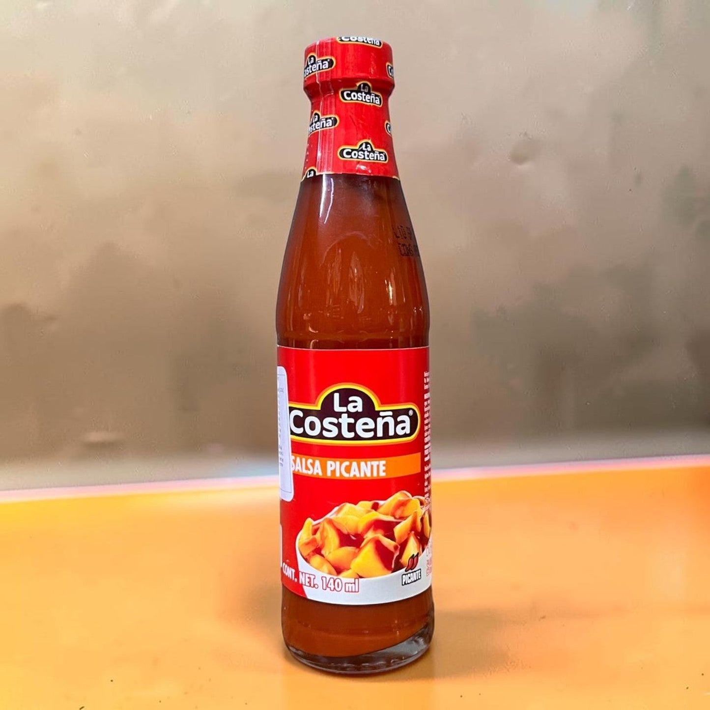 Die Spens Clarens La Costeña Salsa Picante hot sauce in a glass bottle with a red label featuring chopped chilies.