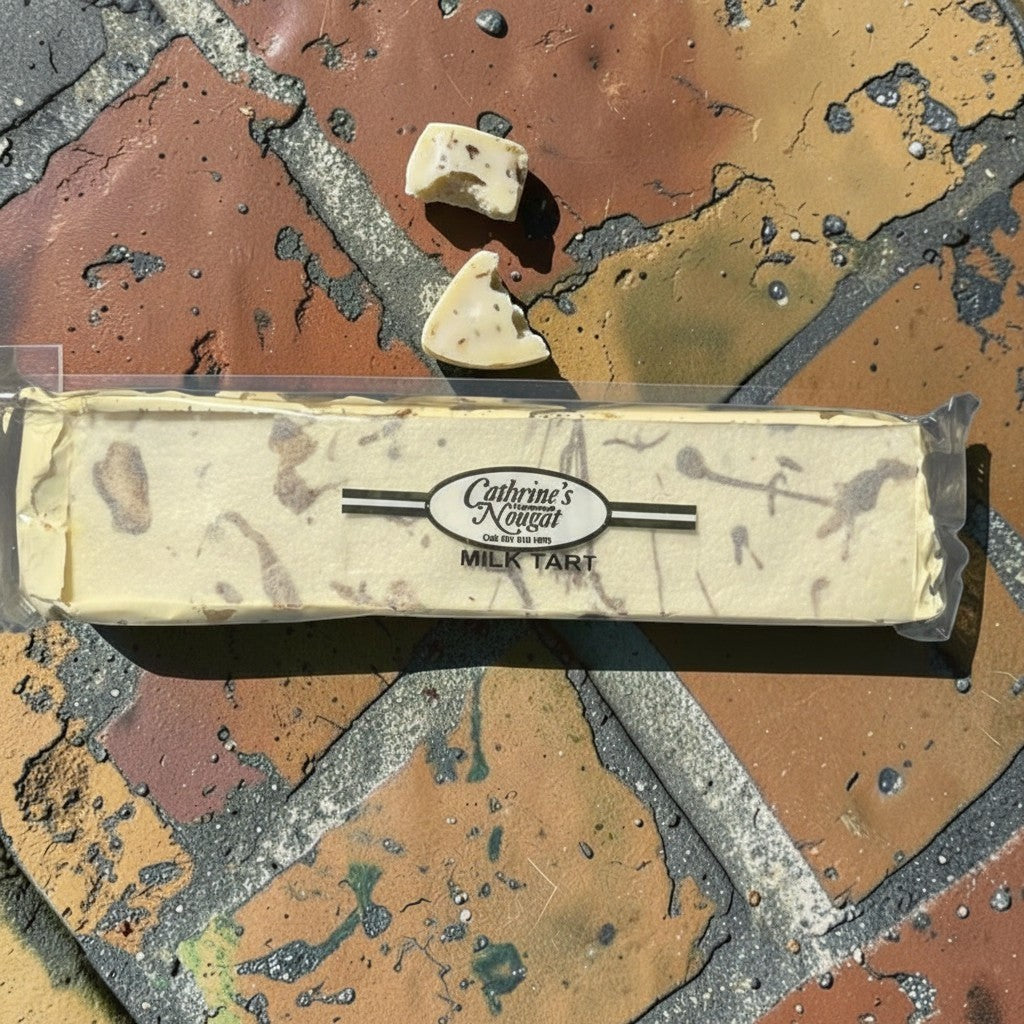 Die Spens Clarens Milk Tart nougat bar with two pieces broken off, showing creamy texture and inclusions.