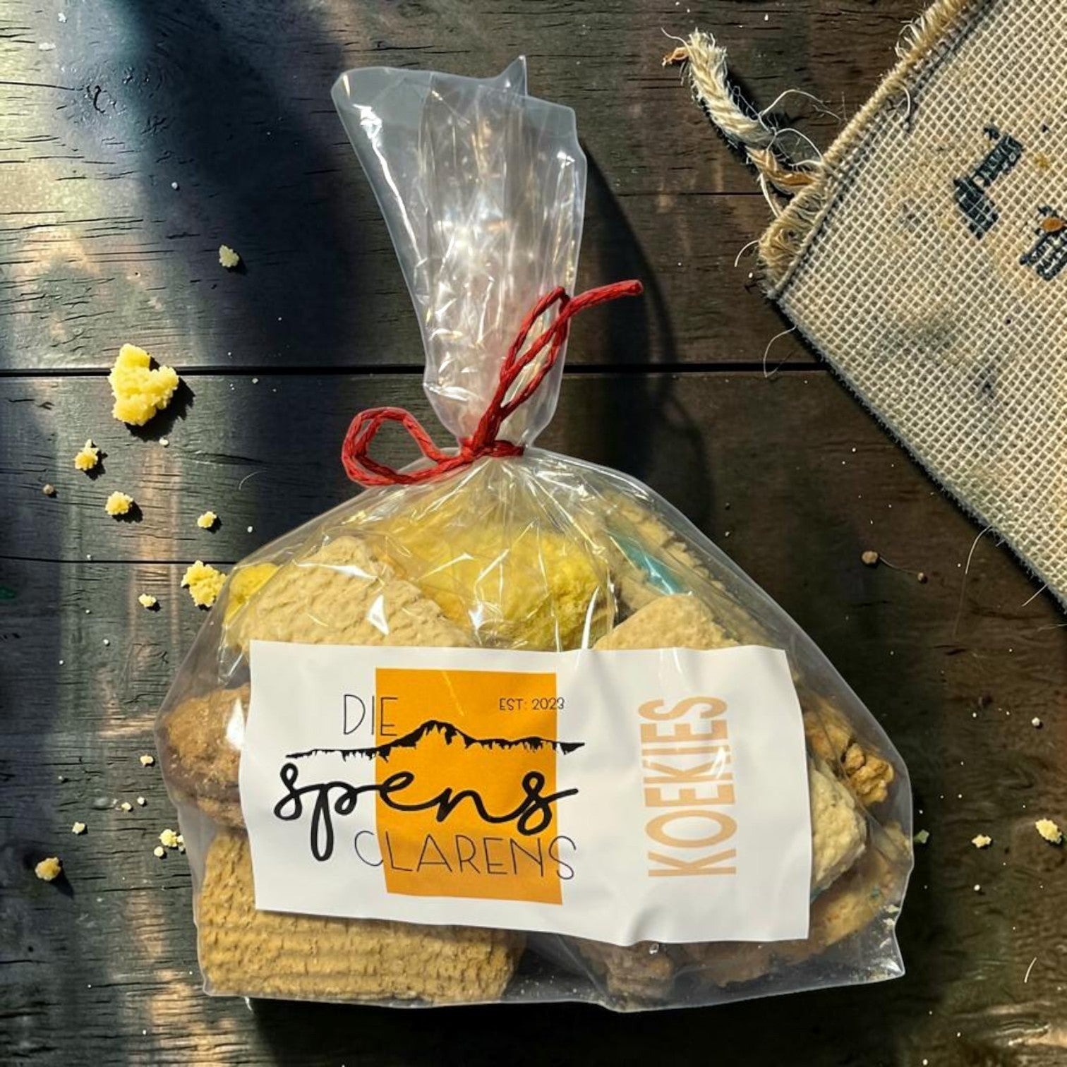 Die Spens Clarens bag of mixed koekies (cookies) with various textures and golden-brown colours, tied with red string.