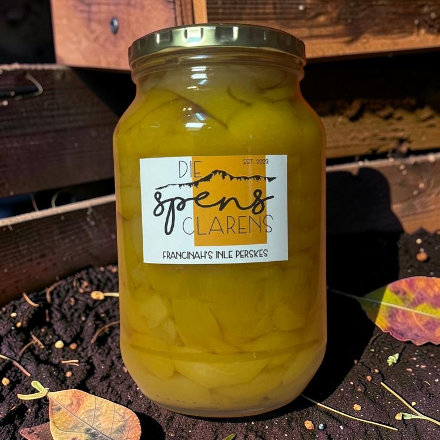 Die Spens Clarens Francinah's Inle Perskes preserved golden peach halves in syrup in a glass jar.