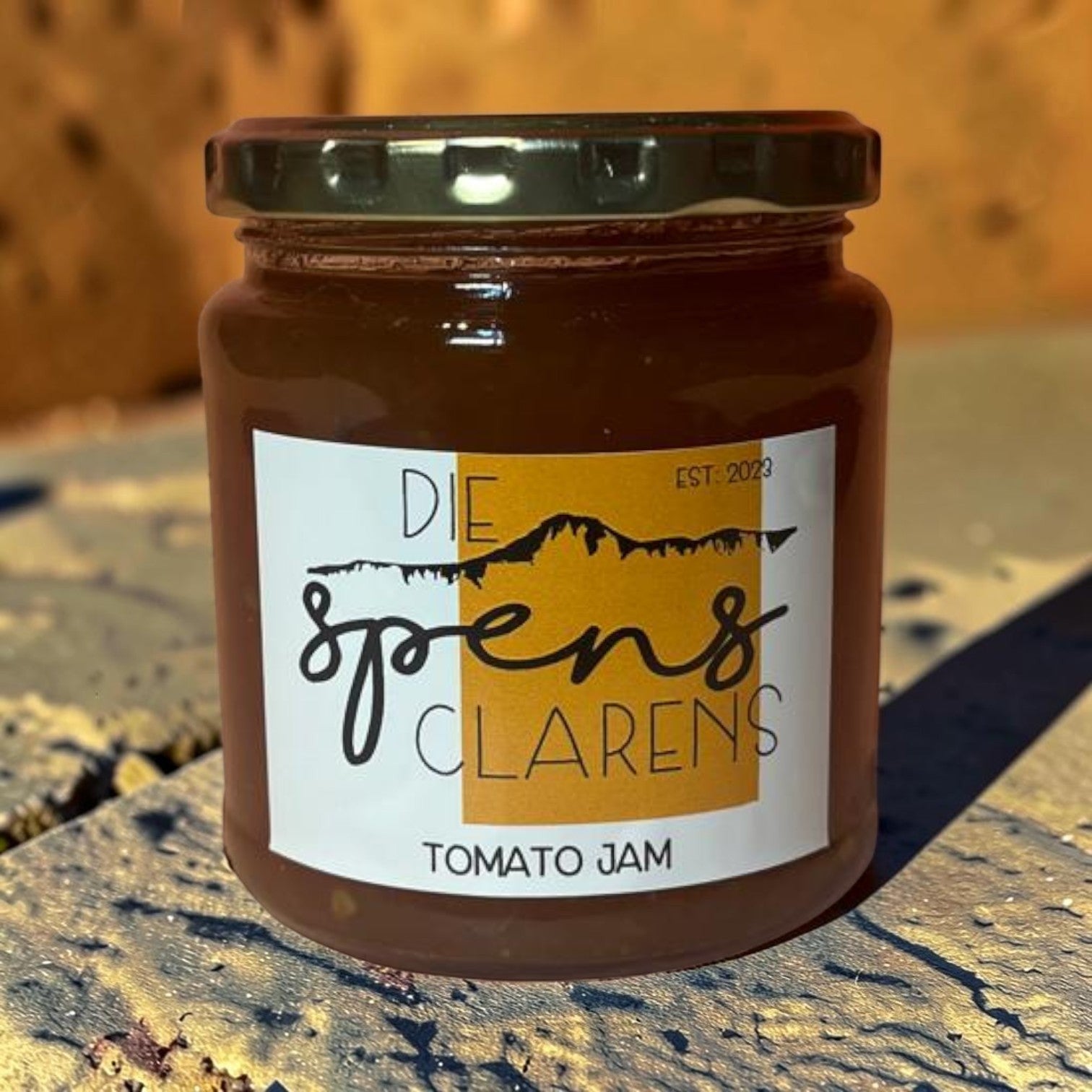 Die Spens Clarens Tomato Jam in a glass jar with a dark lid. The label is white with orange accents and reads 'Die Spens Clarens Tomato Jam'.