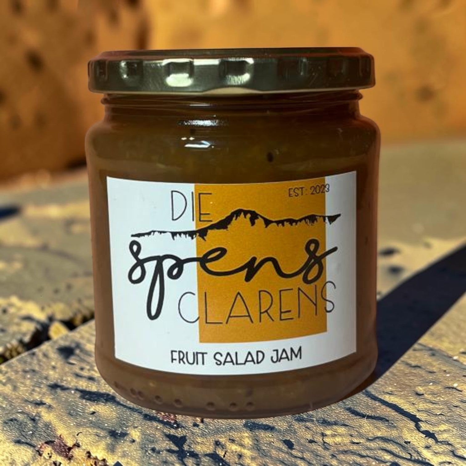 Die Spens Clarens artisanal fruit salad jam in a glass jar with a gold lid. The label features mountains and the text 'Fruit Salad Jam'.