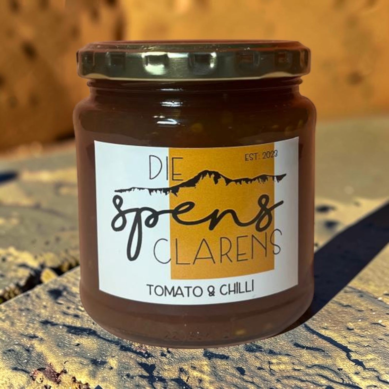 Die Spens Clarens Tomato & Chilli Jam in a glass jar with a gold lid. Artisanal jam with a sweet and spicy flavour.