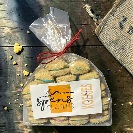 Die Spens Clarens vanilla koekies sandwich cookies with blue and purple cream filling, packaged in a clear bag tied with red string.
