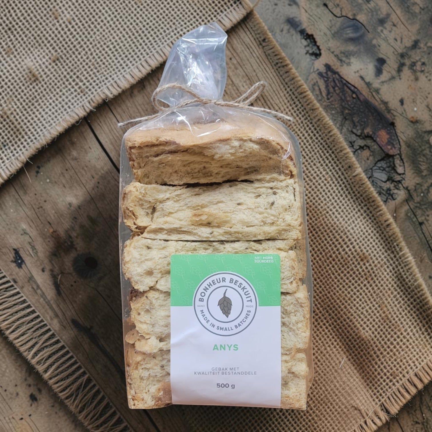 Die Spens Clarens Aniseed Hops biscuits in a clear plastic bag, tied with twine, showing their golden-brown color and textured surface.