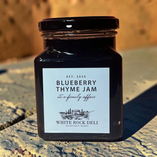Die Spens Clarens Blueberry Thyme Jam in a glass jar with a black lid. Artisanal jam with a dark purple hue.