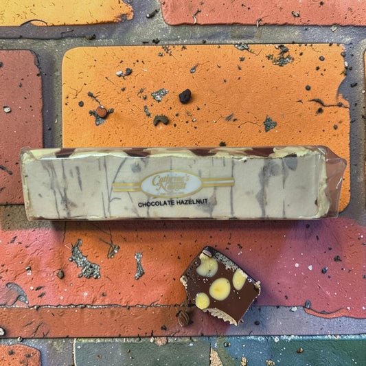 Die Spens Clarens Chocolate Hazelnut Nougat bar with swirls of chocolate and whole hazelnuts, with a sample piece showing chocolate, nougat, and hazelnuts.