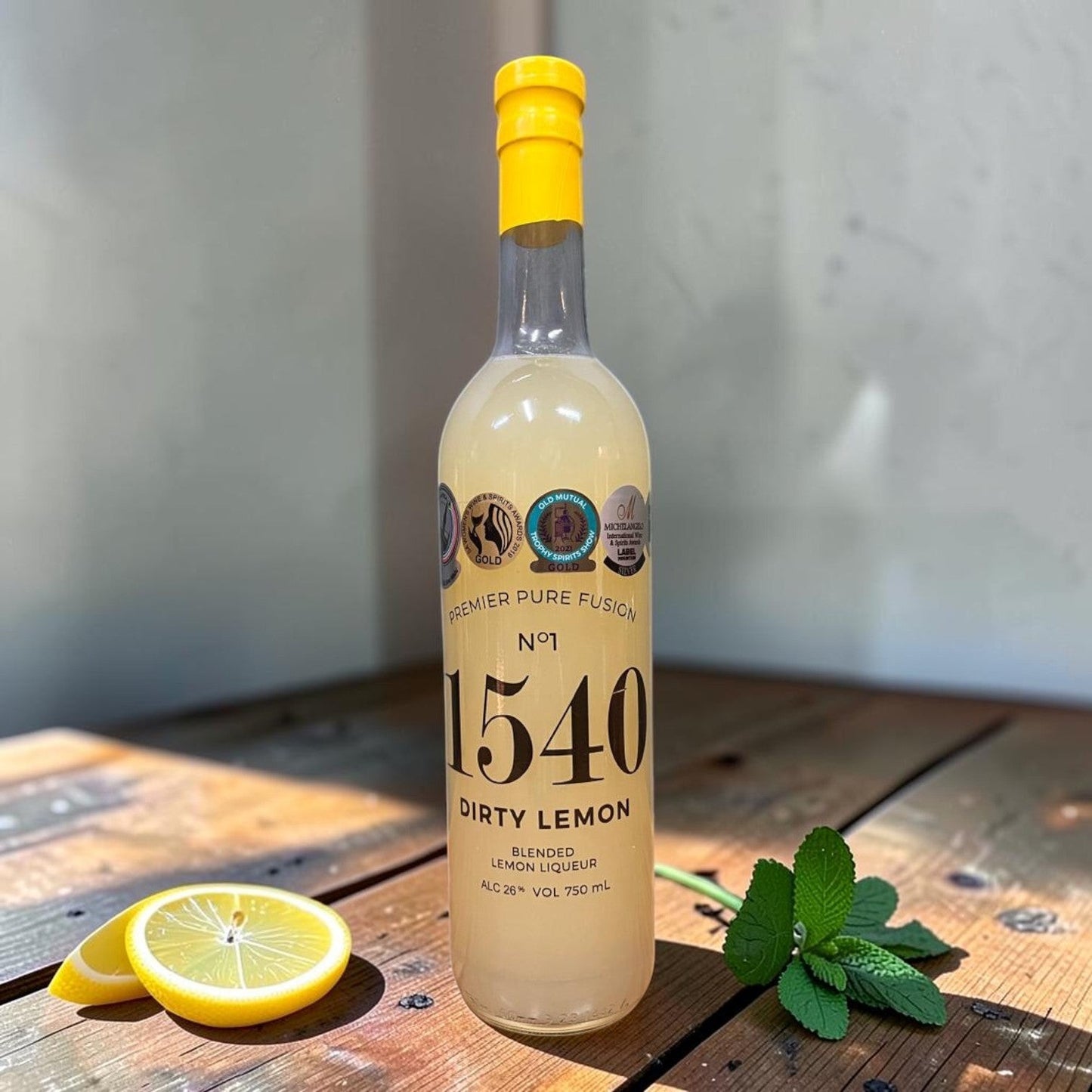 Die Spens Clarens Premier Pure Fusion 1540 Dirty Lemon blended lemon liqueur in a clear bottle with a yellow cap, garnished with lemon slices and mint.