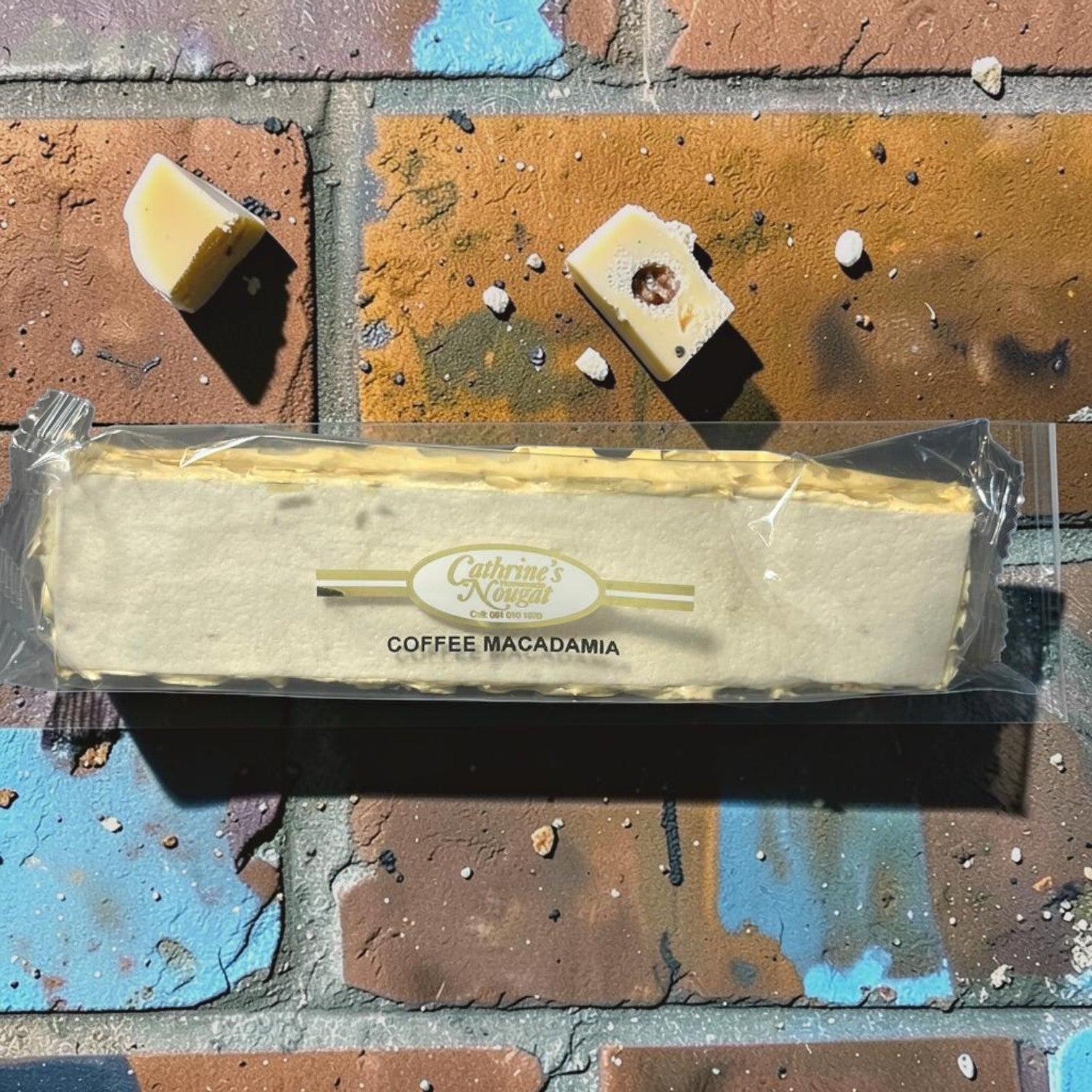 Die Spens Clarens Coffee Macadamia nougat bar with macadamia nuts and coffee flavour. Two pieces are shown broken off.
