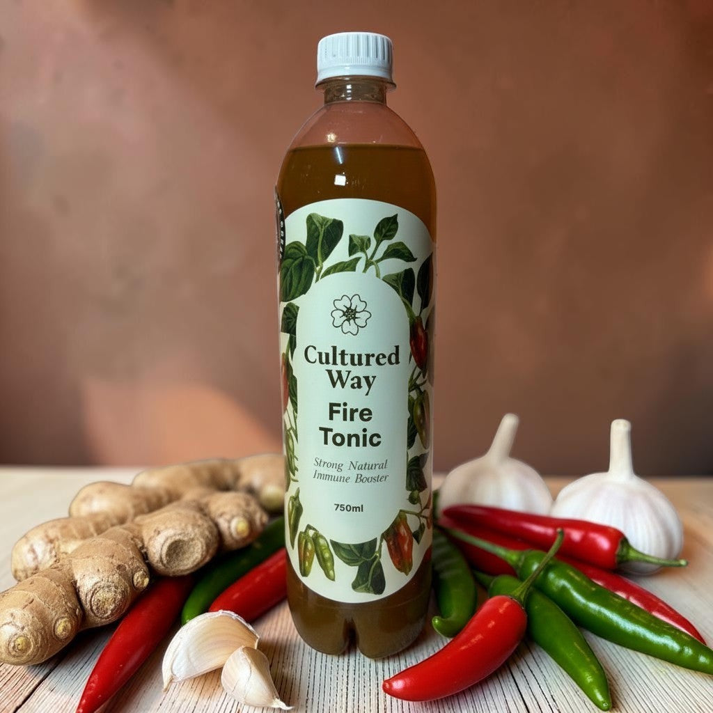 Die Spens Clarens Cultured Way Fire Tonic bottle surrounded by ginger, garlic, and chili peppers. Strong natural immune booster.
