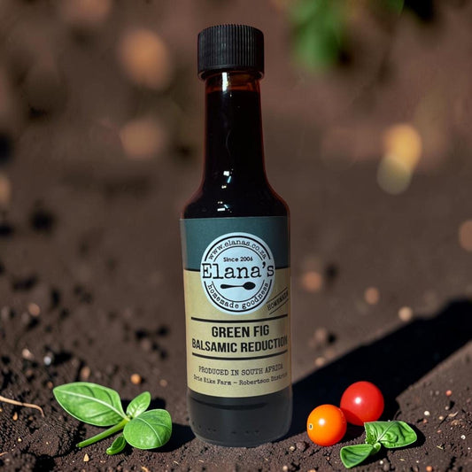 Die Spens Clarens Elana's Green Fig Balsamic Reduction bottle with basil and cherry tomatoes on dark soil.