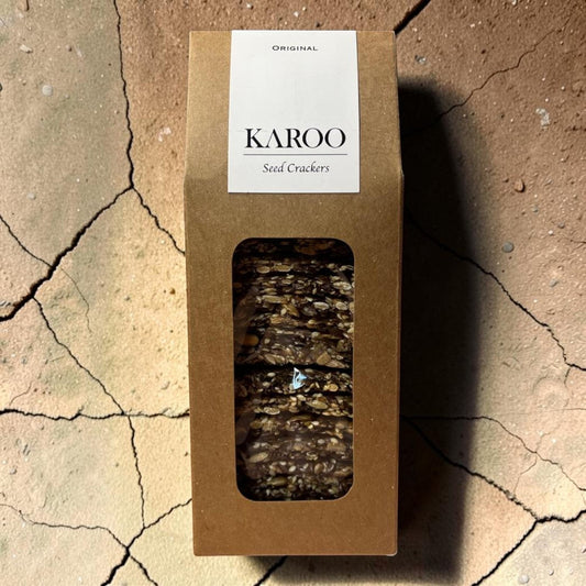 Die Spens Clarens Karoo Ventures Original Seed Crackers in brown packaging with a window showing the seed-filled crackers.