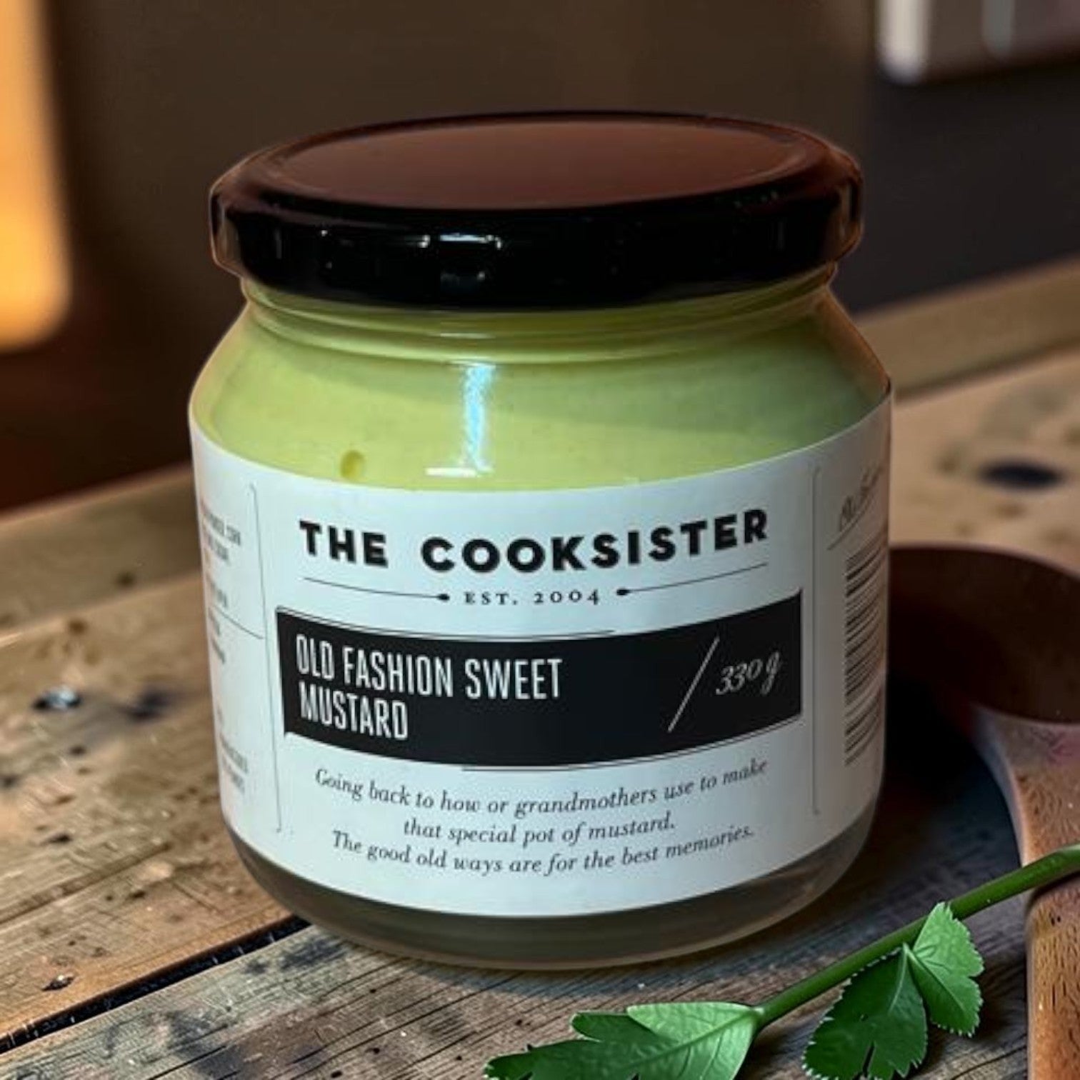 Die Spens Clarens The Cooksister Old Fashion Sweet Mustard in a glass jar with a black lid. Smooth, pale yellow mustard.