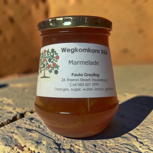 Die Spens Clarens Wegkomkans B&B orange marmalade in a glass jar with a gold lid. Features a label with a tree illustration and ingredients.