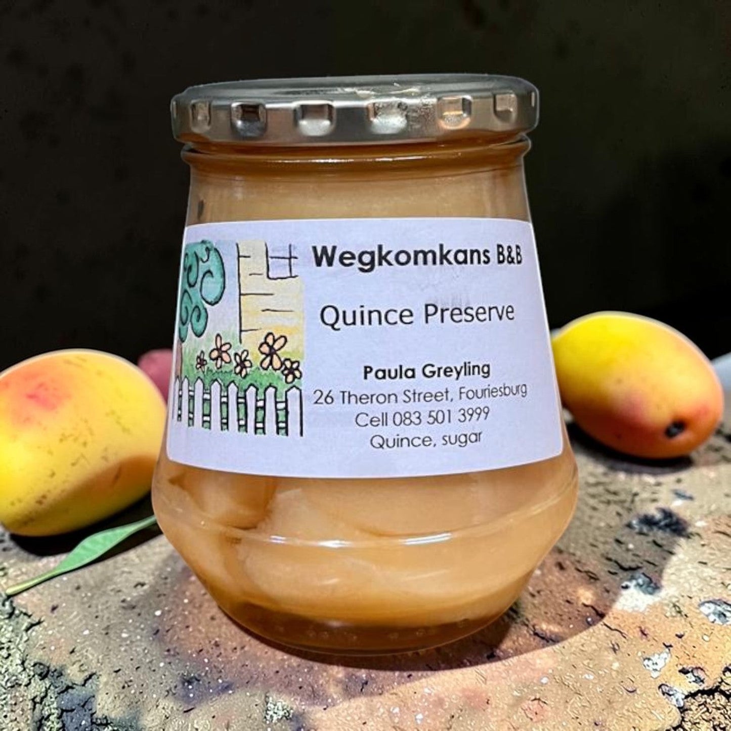 Die Spens Clarens Wegkomkans B&B Quince Preserve in a glass jar, with two quinces beside it.