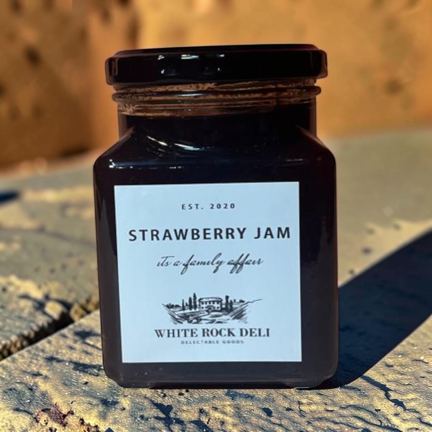 Die Spens Clarens White Rock Deli Strawberry Jam in a glass jar with a black lid. Classic fruit spread.