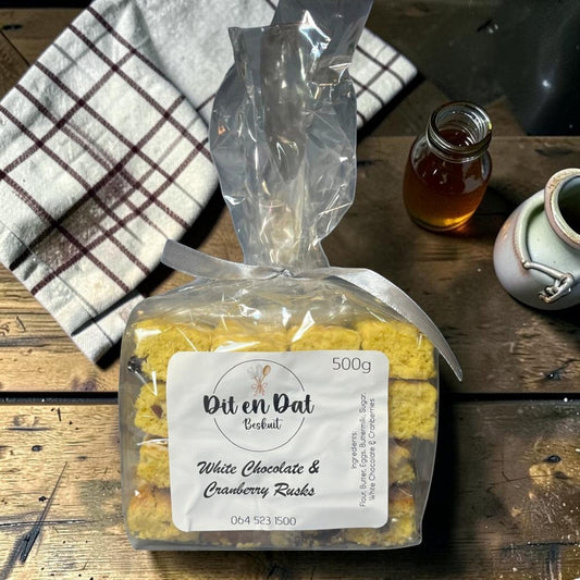 Die Spens Clarens White Chocolate & Cranberry Rusks in a clear bag, 500g pack, with a checkered cloth and honey.
