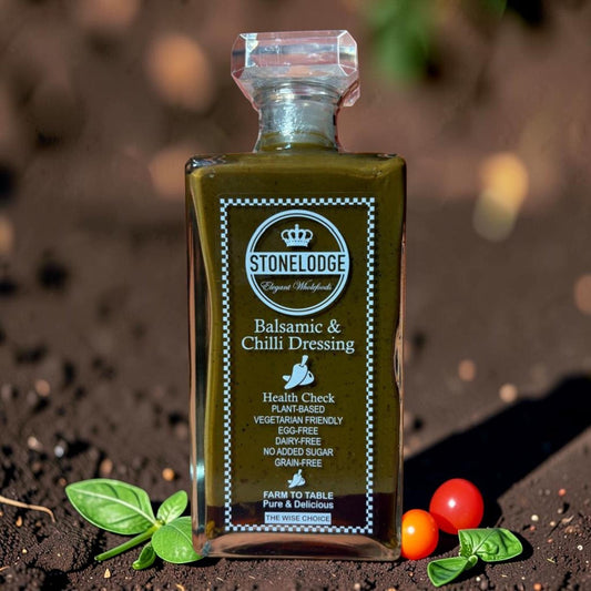 Die Spens Clarens Stonelodge Balsamic & Chilli Dressing bottle with fresh basil and cherry tomatoes on soil.