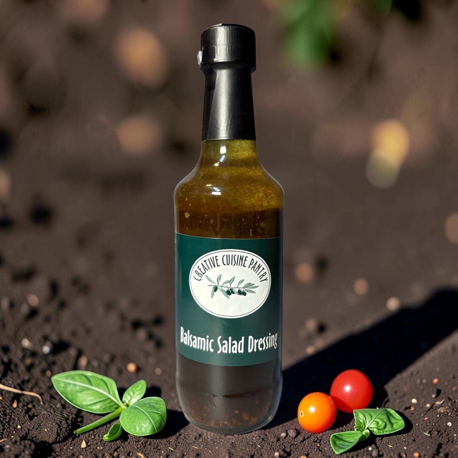 Die Spens Clarens Balsamic Salad Dressing in a glass bottle with a black cap, surrounded by fresh basil and cherry tomatoes on dark soil.