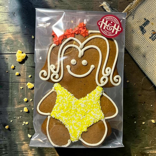 Die Spens Clarens gingerbread cookie shaped like a woman in a yellow bikini, decorated with white icing and orange details.