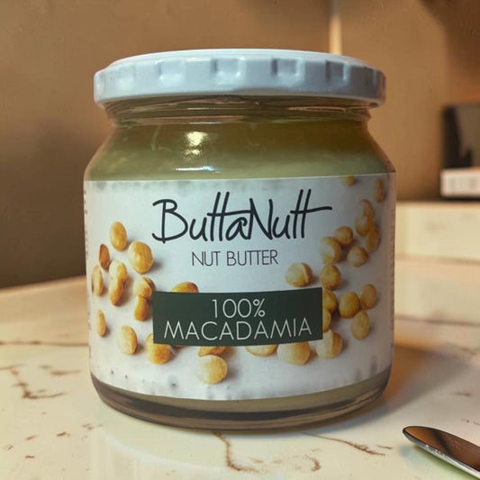 Die Spens Clarens ButtaNutt 100% Macadamia Nut Butter in a glass jar with a white lid. Smooth, creamy spread with whole macadamia nuts on the label.