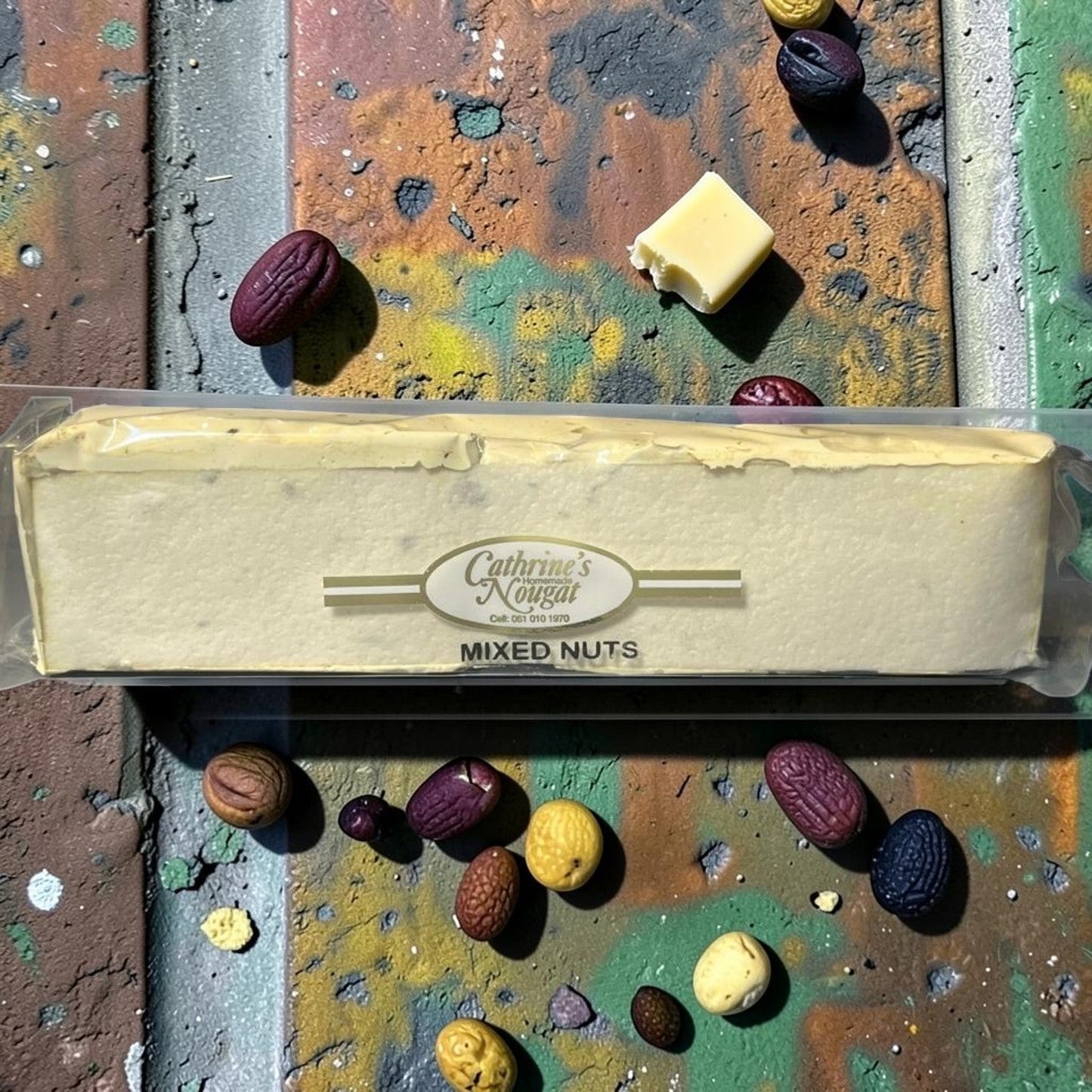 Die Spens Clarens homemade mixed nut nougat bar, packed with various nuts, on a colourful abstract background.