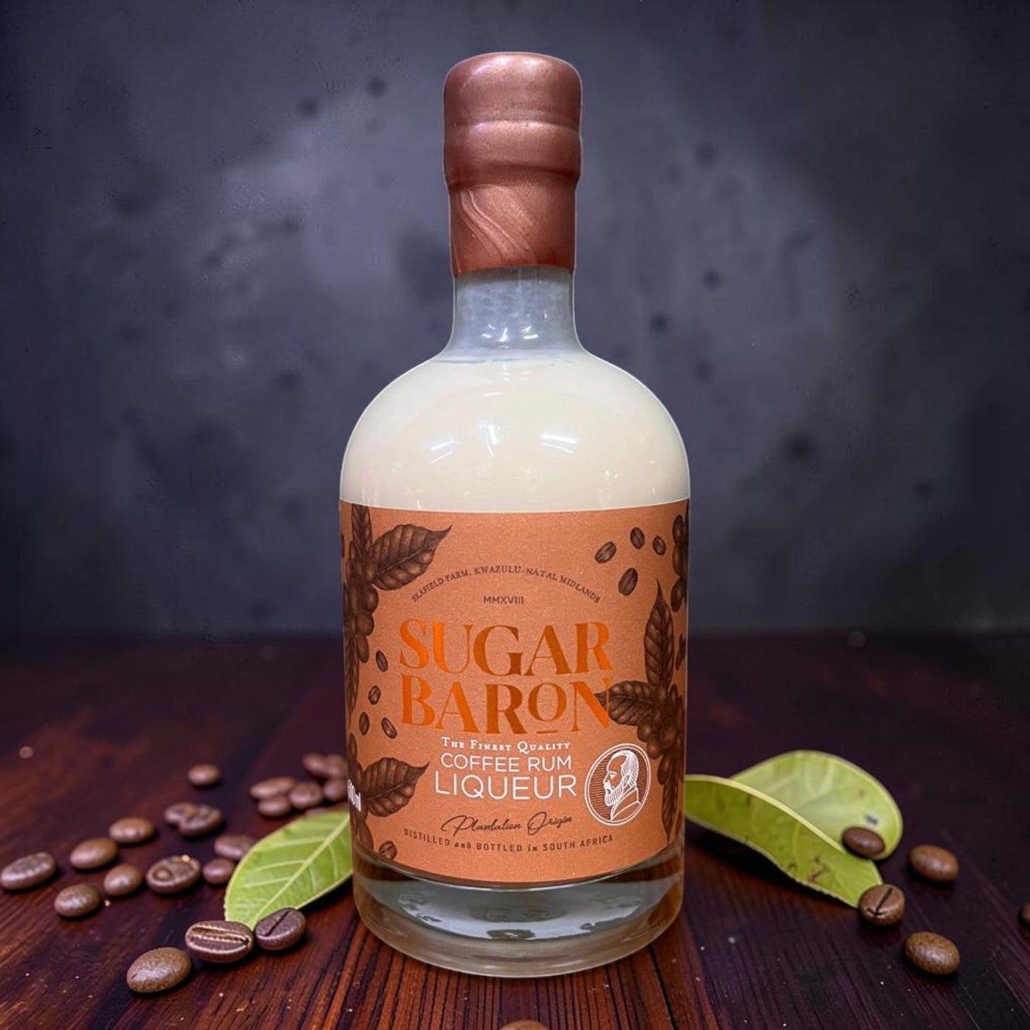 Die Spens Clarens Sugar Baron Coffee Rum Liqueur bottle with creamy beige liquid and copper cap, surrounded by coffee beans.